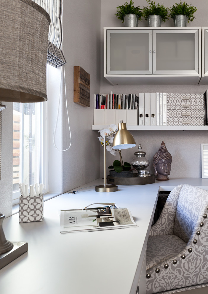На фото: домашняя мастерская среднего размера в стиле неоклассика (современная классика) с серыми стенами, полом из ламината и встроенным рабочим столом с