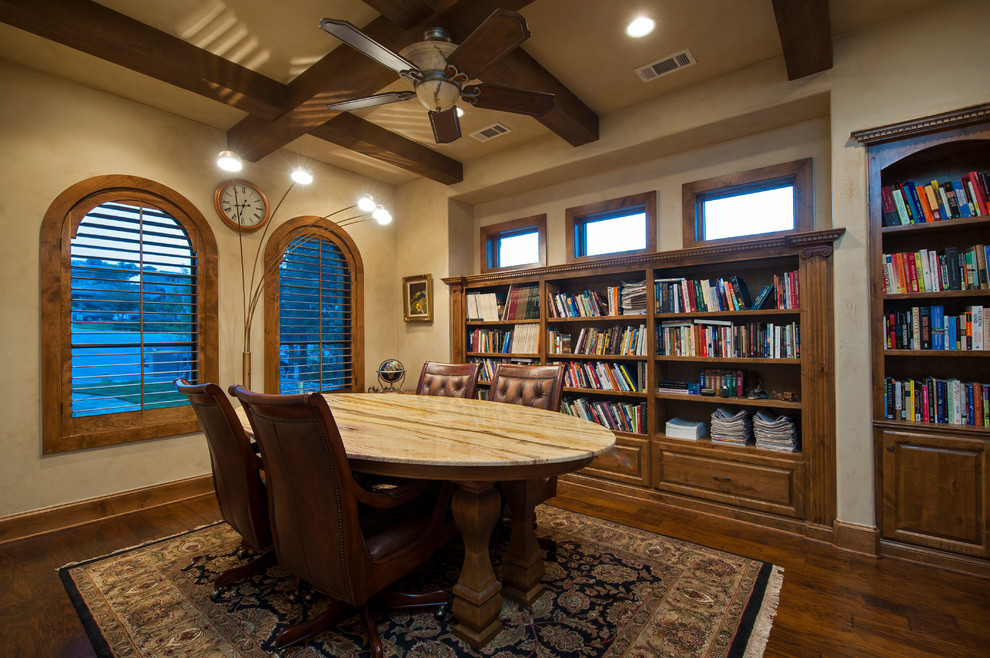 This is an example of a mediterranean home office in Austin with beige walls, dark hardwood flooring and a freestanding desk.