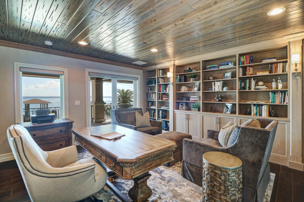 Großes Mediterranes Arbeitszimmer mit Arbeitsplatz, grauer Wandfarbe, braunem Holzboden, freistehendem Schreibtisch und braunem Boden in Tampa