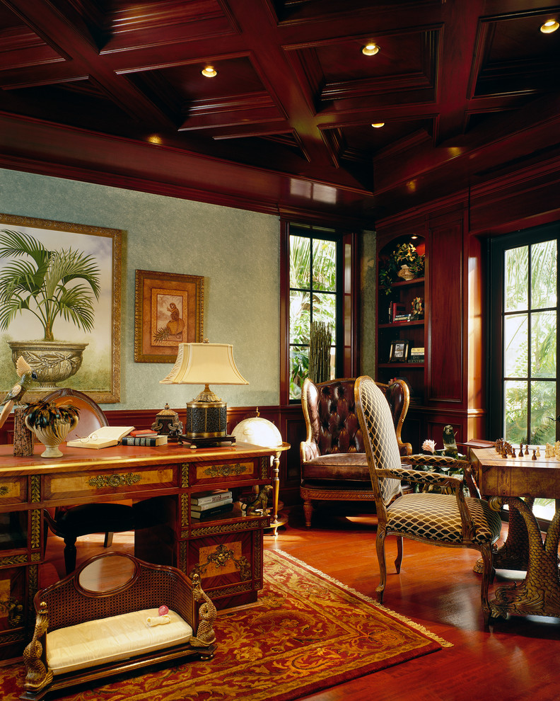 Großes Mediterranes Arbeitszimmer mit braunem Holzboden, freistehendem Schreibtisch, Arbeitsplatz, grüner Wandfarbe und braunem Boden in Miami