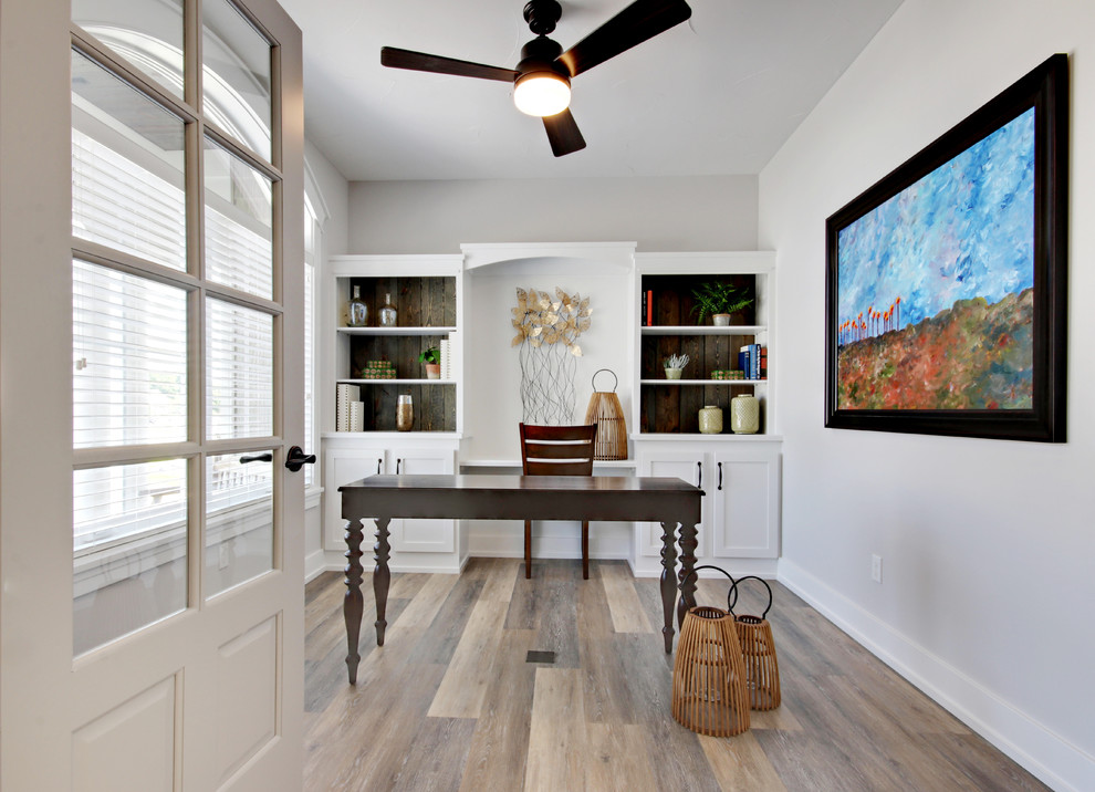 Inspiration for a traditional study in Grand Rapids with white walls, light hardwood flooring, a freestanding desk and beige floors.