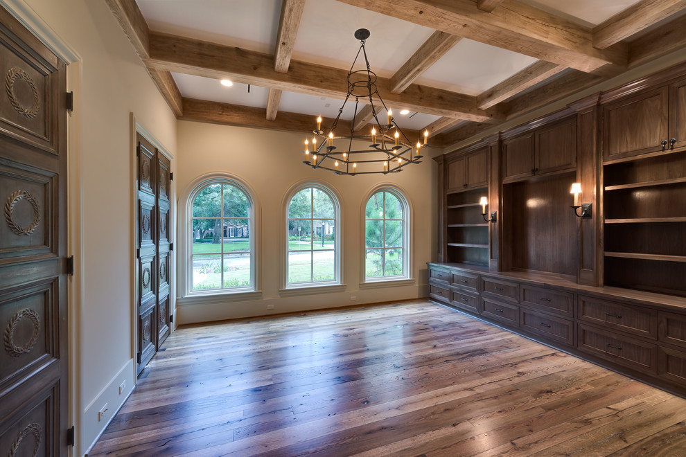 Example of a large tuscan built-in desk medium tone wood floor study room design in Houston with beige walls