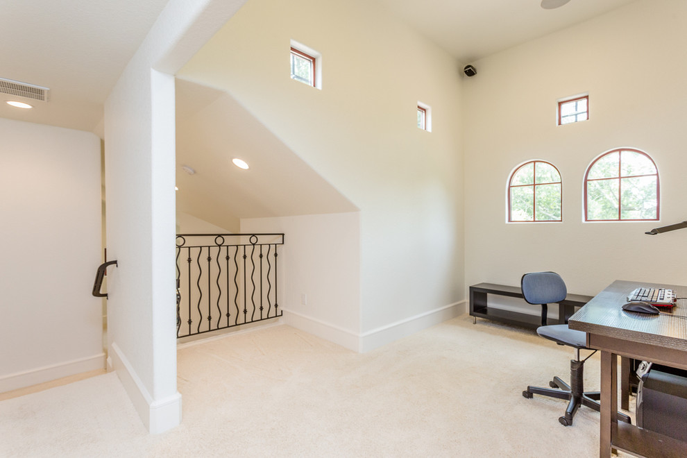 Foto på ett stort medelhavsstil hemmastudio, med vita väggar, heltäckningsmatta, ett fristående skrivbord och vitt golv