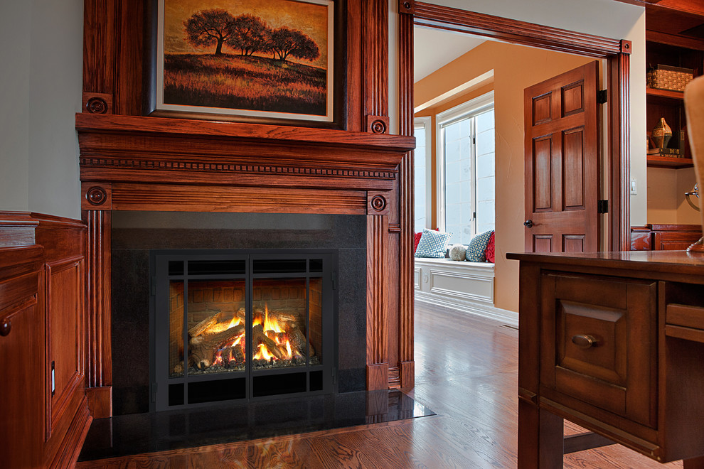 Example of a large mountain style freestanding desk medium tone wood floor and brown floor home office design in Boston with gray walls, a standard fireplace and a wood fireplace surround
