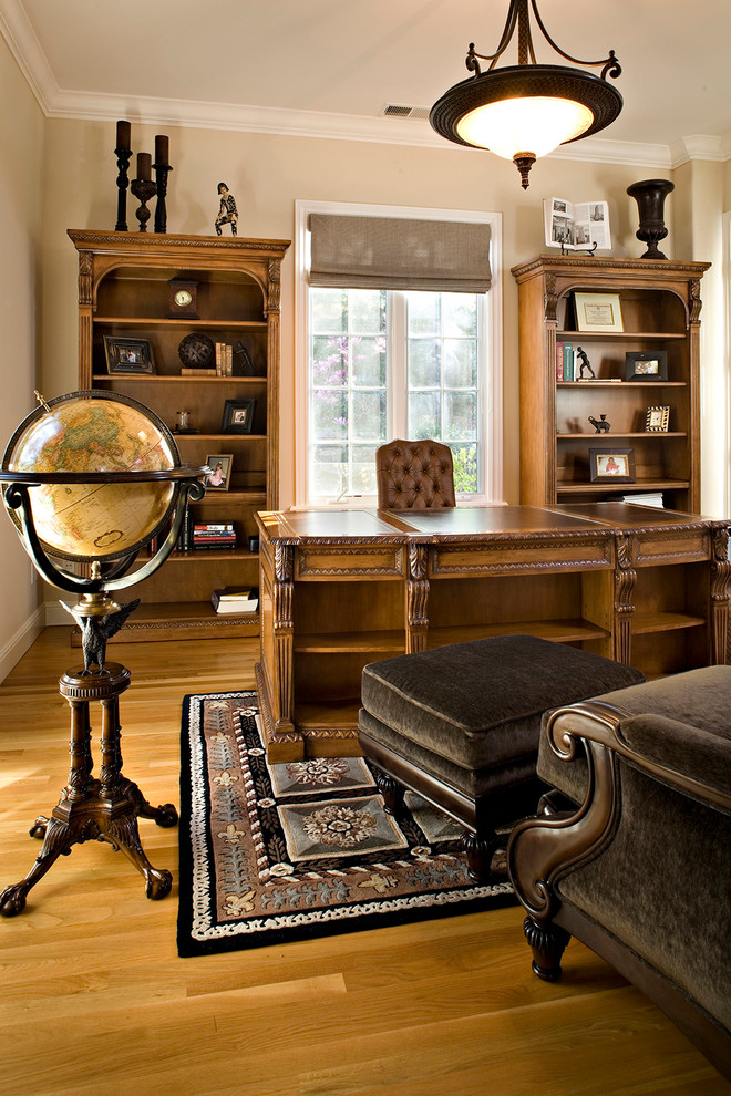 Modelo de despacho clásico grande con paredes beige, suelo de madera clara y escritorio independiente