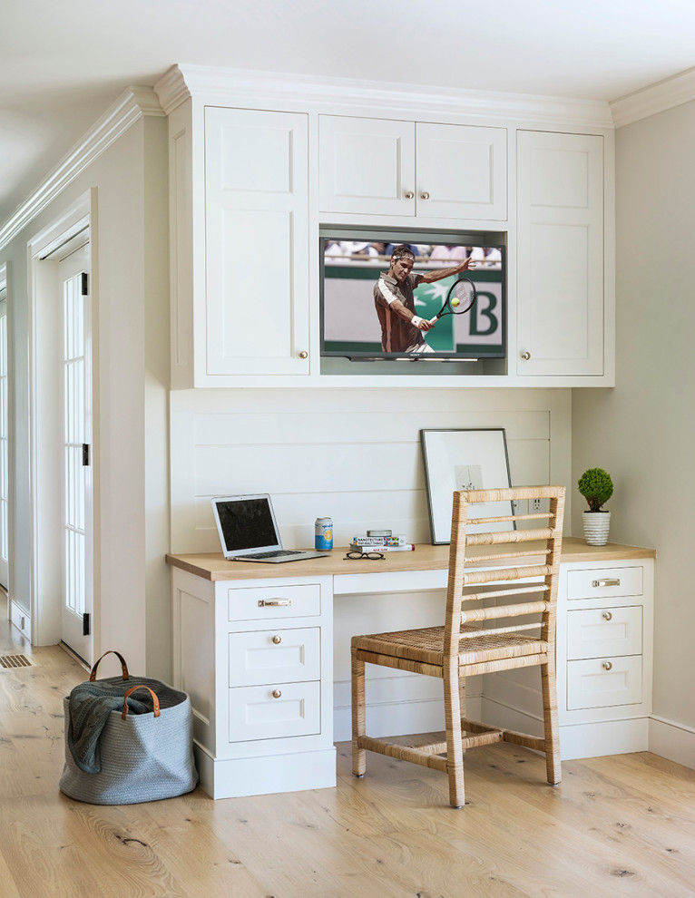 Imagen de despacho marinero con paredes blancas, suelo de madera clara, escritorio empotrado y suelo beige