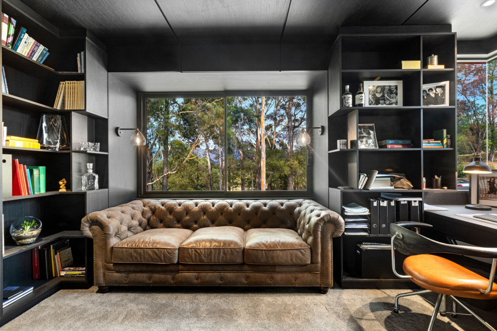 サンシャインコーストにある高級なコンテンポラリースタイルのおしゃれなホームオフィス・書斎 (黒い壁、カーペット敷き、造り付け机、グレーの床、ライブラリー、羽目板の壁) の写真