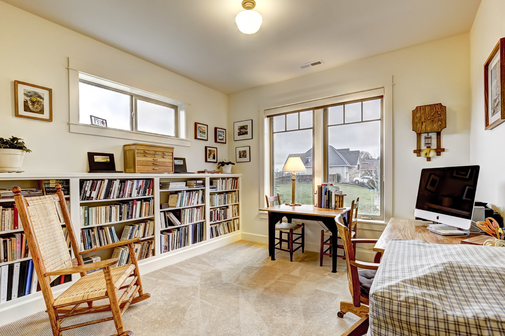 Amerikansk inredning av ett mellanstort arbetsrum, med ett bibliotek, heltäckningsmatta, ett fristående skrivbord och vita väggar