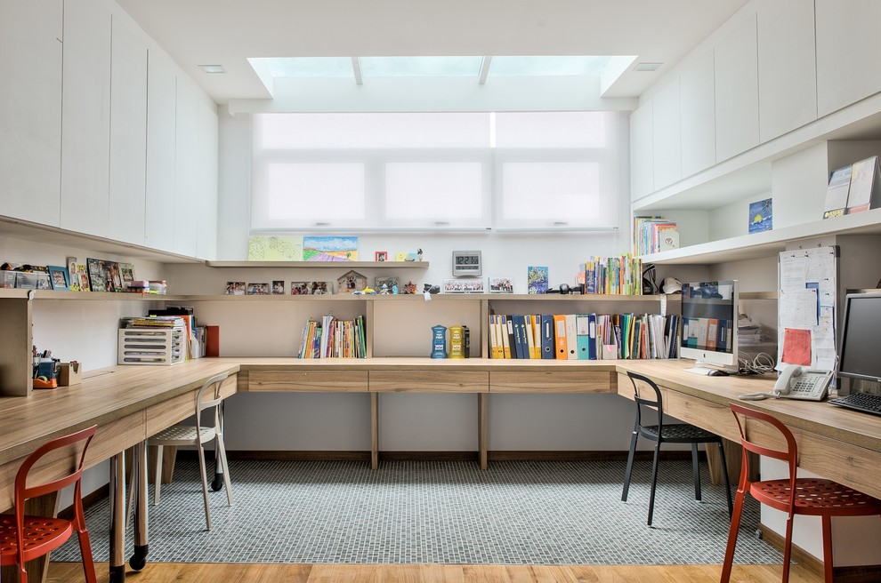 Inspiration för stora moderna hemmabibliotek, med vita väggar, ljust trägolv och ett inbyggt skrivbord