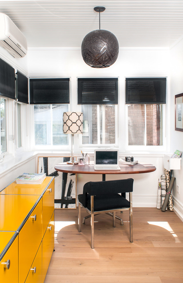 Immagine di uno studio minimal di medie dimensioni con pareti bianche, pavimento in legno massello medio e scrivania autoportante
