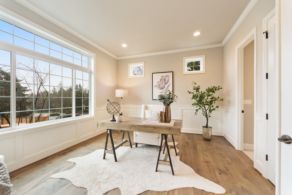 Klassisches Arbeitszimmer mit beiger Wandfarbe, braunem Holzboden, freistehendem Schreibtisch, braunem Boden und vertäfelten Wänden in Seattle