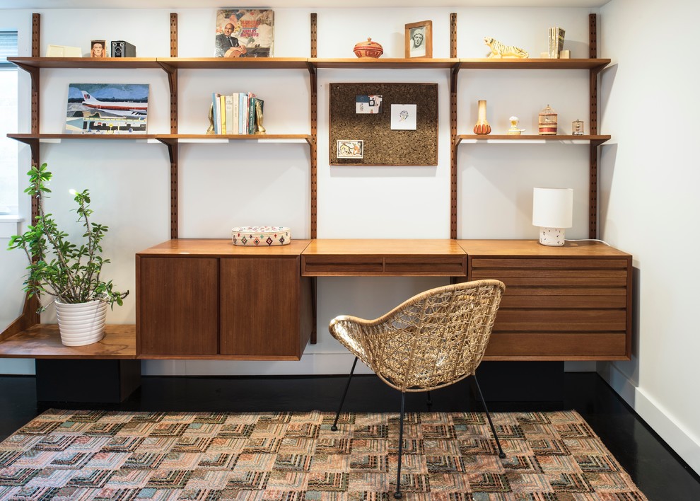 Modern inredning av ett litet arbetsrum, med vita väggar, betonggolv, ett inbyggt skrivbord och svart golv