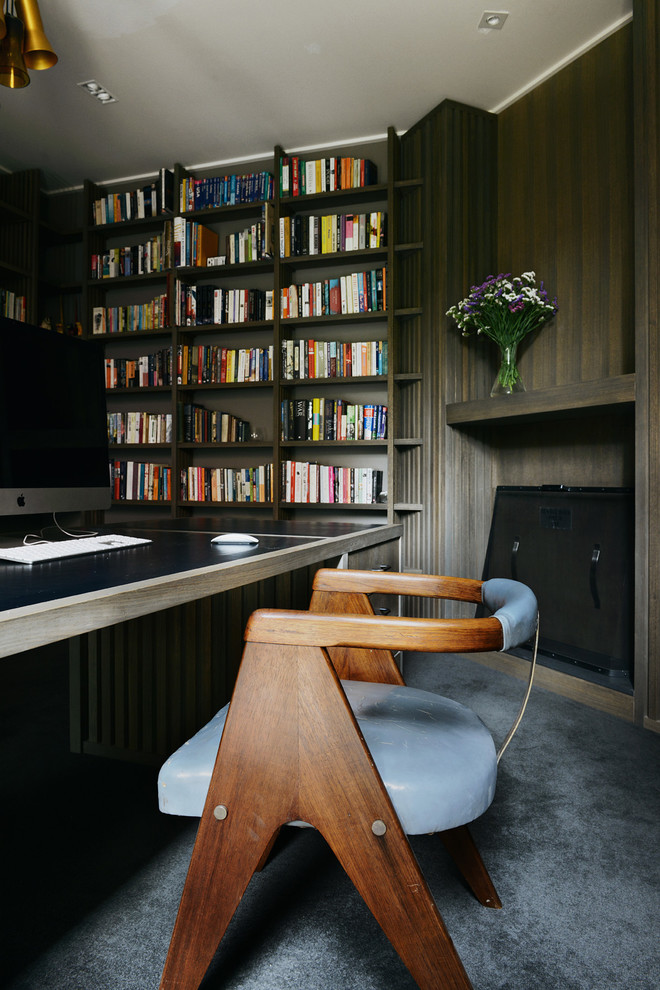 Bild på ett hemmabibliotek, med bruna väggar och heltäckningsmatta