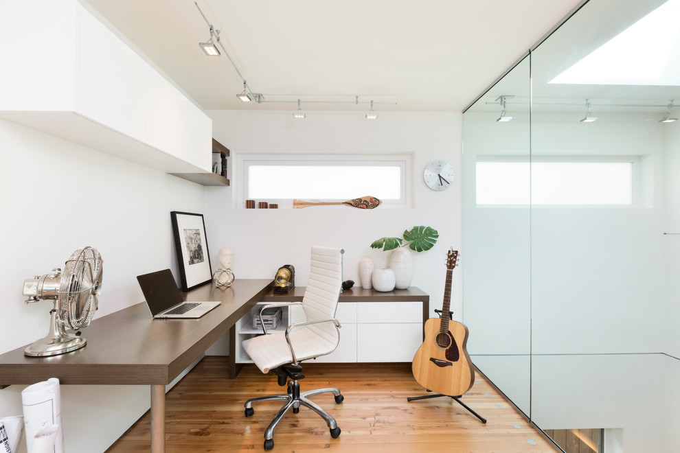 Idee per uno studio design con pareti bianche, pavimento in legno massello medio e scrivania autoportante