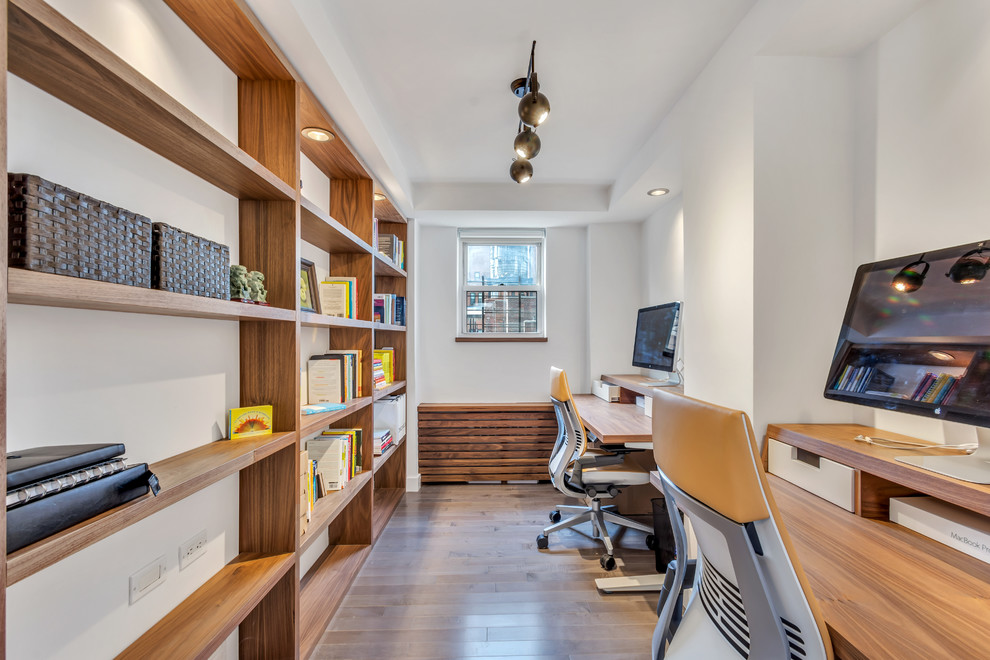 Mittelgroßes Modernes Arbeitszimmer ohne Kamin mit dunklem Holzboden, freistehendem Schreibtisch, Arbeitsplatz, weißer Wandfarbe und braunem Boden in New York