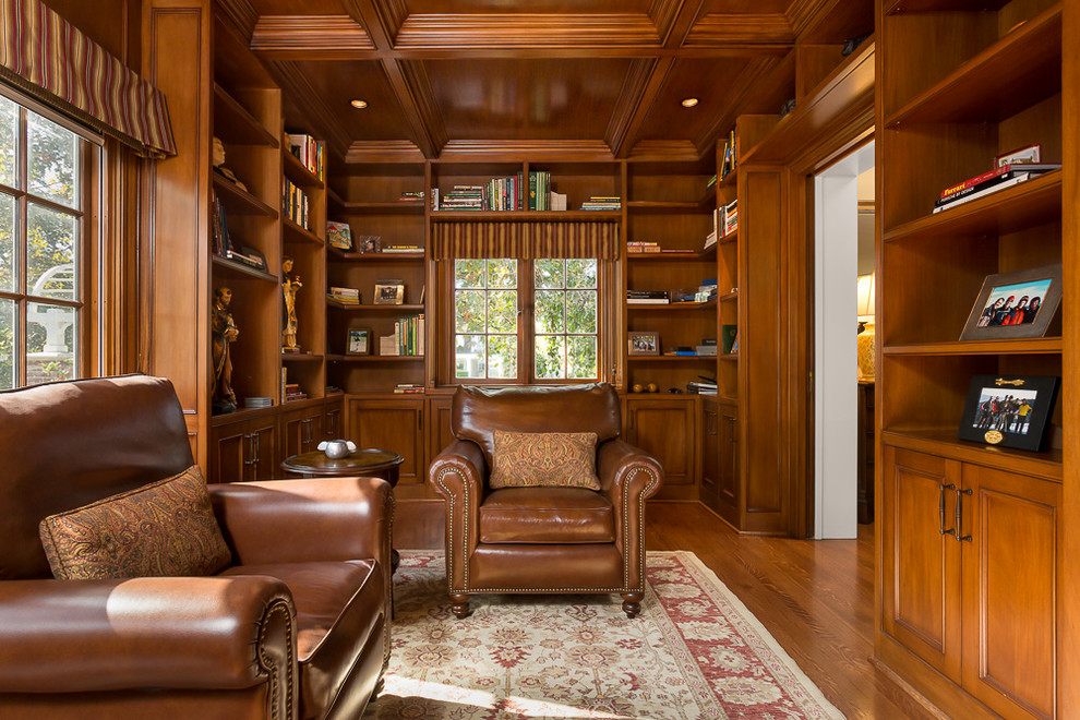 Esempio di uno studio chic con libreria, pareti marroni, pavimento in legno massello medio, camino ad angolo e cornice del camino in pietra