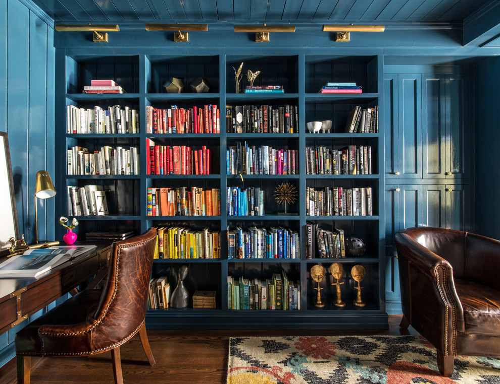 Bild på ett vintage arbetsrum, med ett bibliotek, blå väggar, mörkt trägolv och ett fristående skrivbord