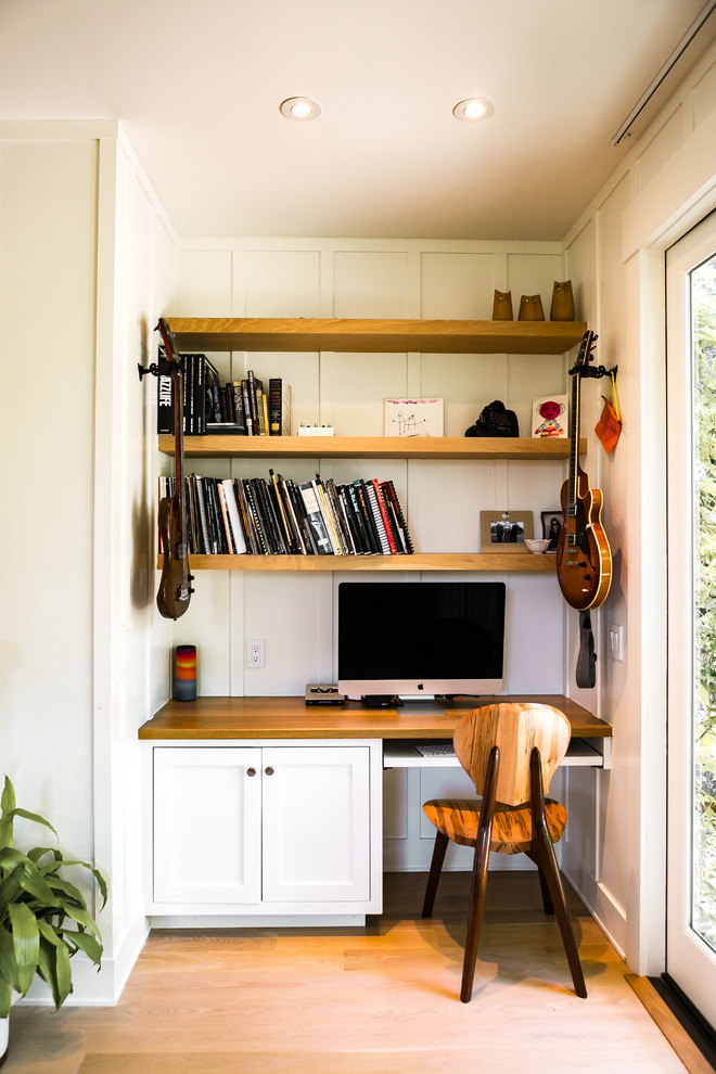 Example of a transitional built-in desk medium tone wood floor and brown floor home office design in San Francisco with white walls