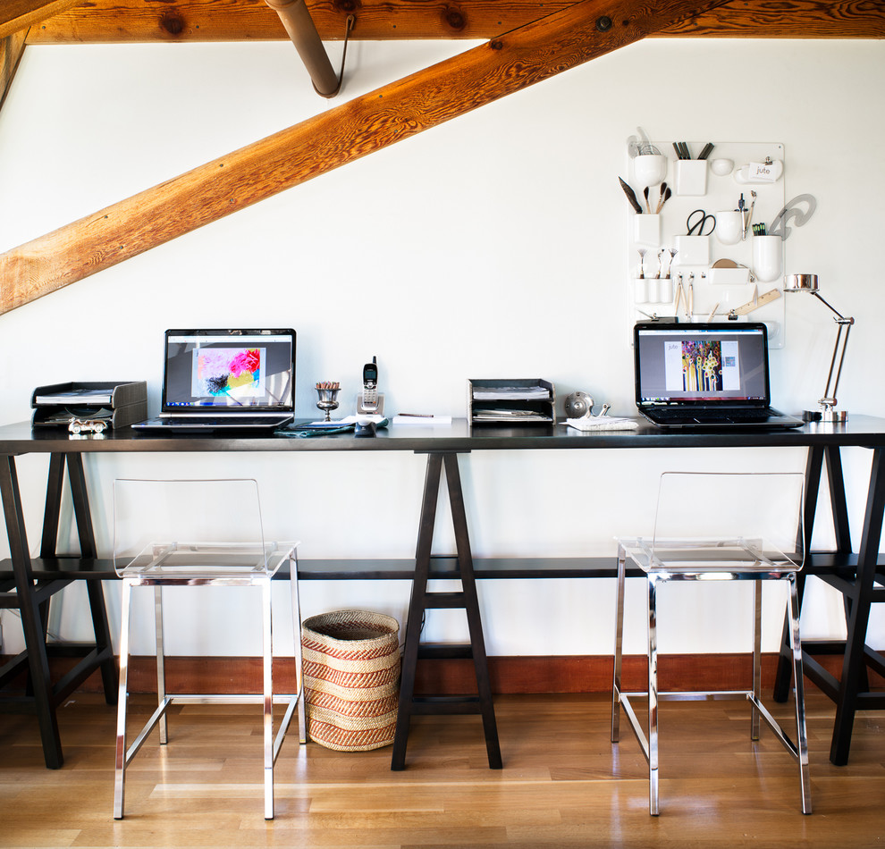Modelo de despacho contemporáneo con paredes blancas, suelo de madera en tonos medios y escritorio independiente