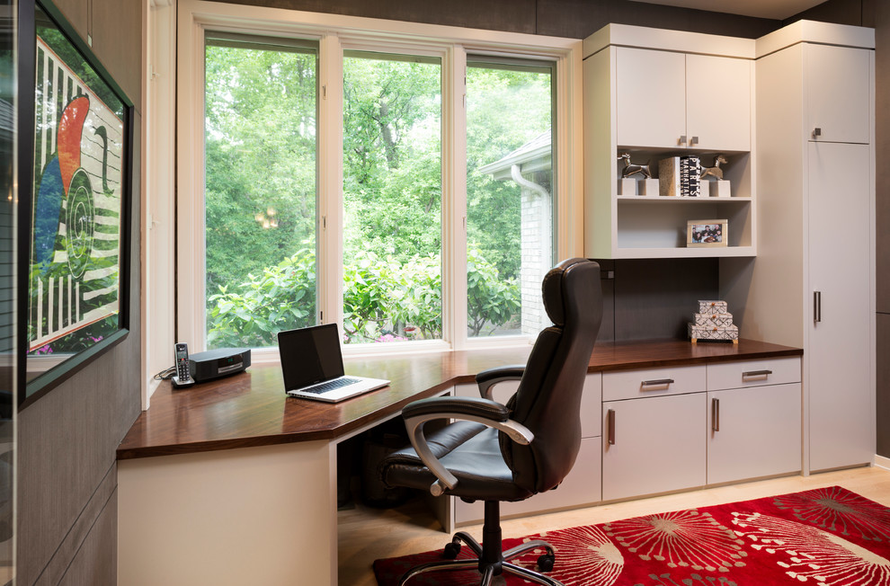 This is an example of a contemporary study in Minneapolis with grey walls, light hardwood flooring and a built-in desk.