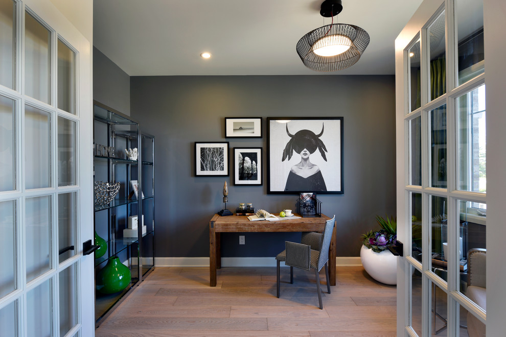 Imagen de despacho actual con paredes grises, suelo de madera clara, escritorio independiente y suelo marrón