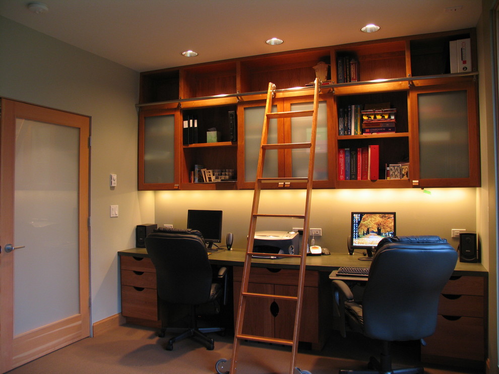 Foto på ett stort funkis hemmabibliotek, med gröna väggar, heltäckningsmatta och ett inbyggt skrivbord