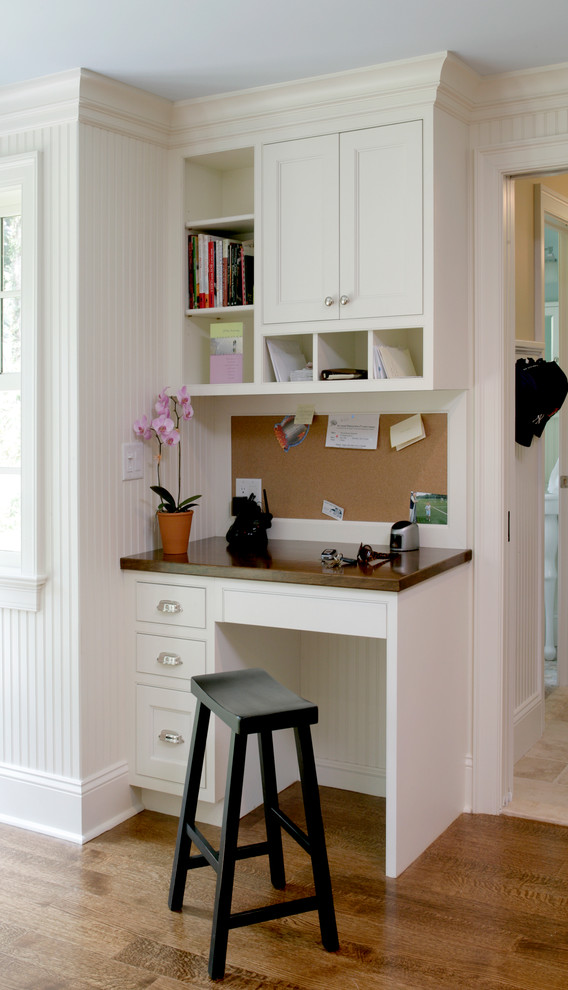 Cette photo montre un bureau chic avec un mur blanc, un sol en bois brun et un bureau intégré.