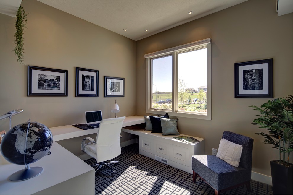 Home office - mid-sized modern built-in desk carpeted home office idea in Omaha with beige walls