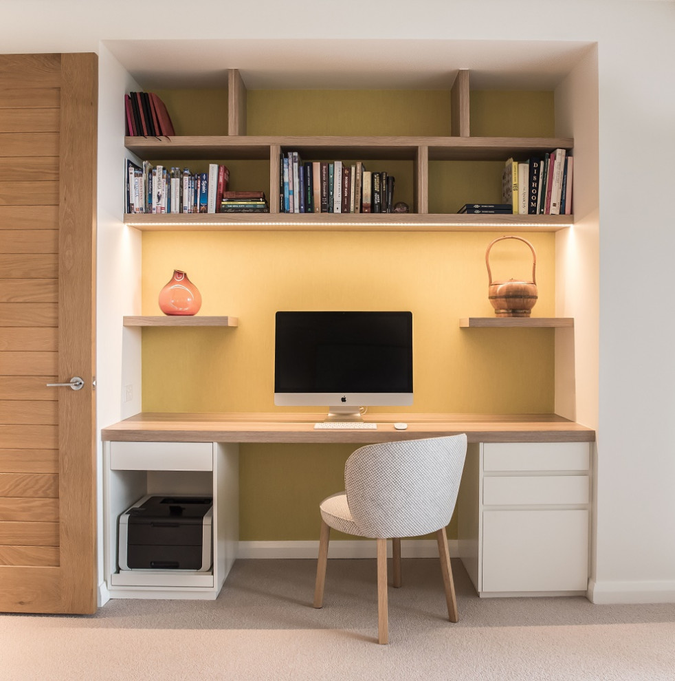 Foto de despacho actual pequeño con paredes amarillas, moqueta, escritorio empotrado, suelo beige y papel pintado