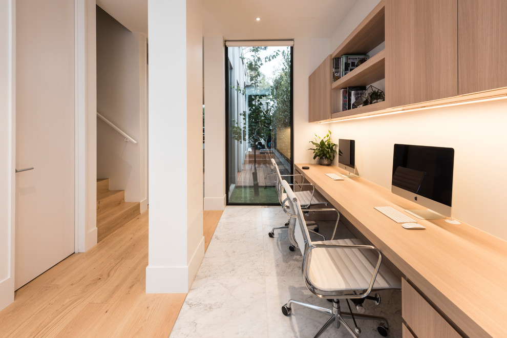 Modelo de despacho actual de tamaño medio con paredes blancas, escritorio empotrado y suelo blanco