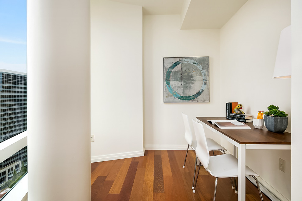 Foto di uno studio contemporaneo di medie dimensioni con pareti bianche, scrivania incassata e pavimento in legno massello medio