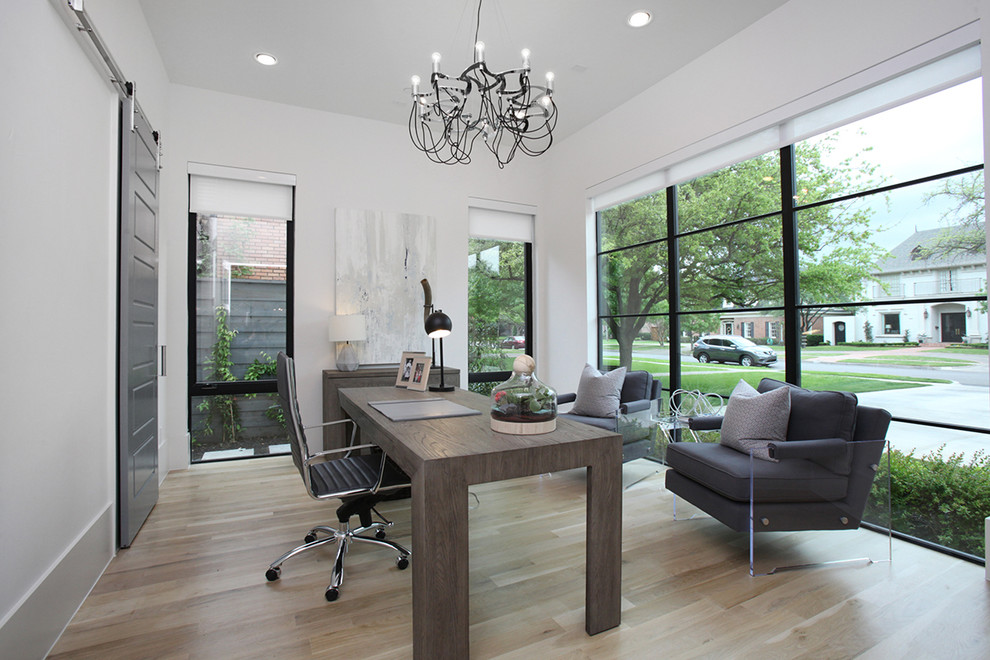 Imagen de despacho minimalista grande sin chimenea con paredes blancas, suelo de madera clara, escritorio independiente y suelo beige