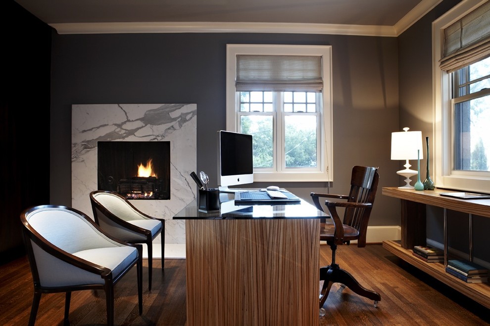 シアトルにある広いコンテンポラリースタイルのおしゃれな書斎 (グレーの壁、無垢フローリング、標準型暖炉、自立型机、石材の暖炉まわり、茶色い床) の写真