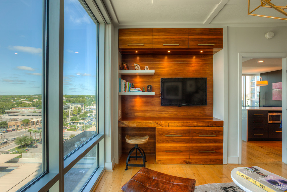 Modernes Arbeitszimmer ohne Kamin mit Arbeitsplatz, weißer Wandfarbe, braunem Holzboden, Einbau-Schreibtisch und braunem Boden in Austin