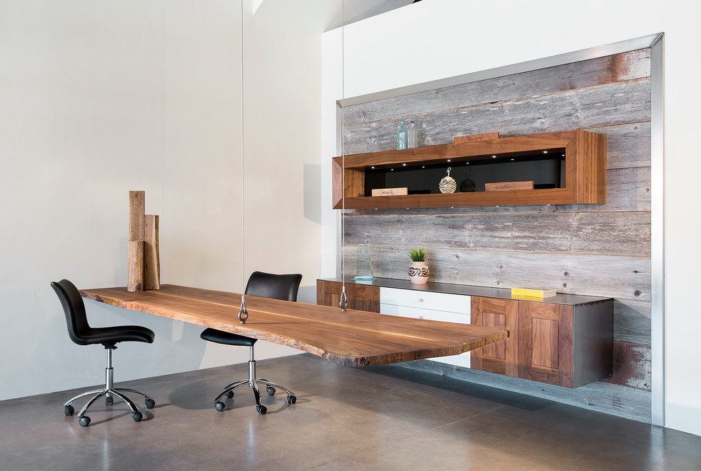Foto på ett stort funkis arbetsrum, med vita väggar, betonggolv, ett fristående skrivbord och brunt golv