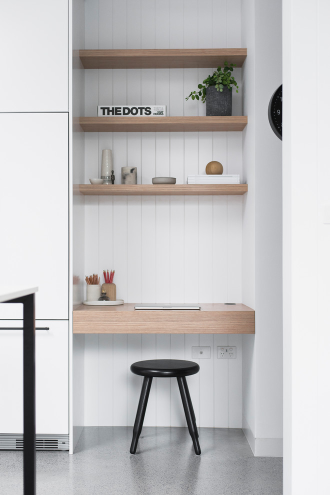 Photo of a large modern home office in Sydney with concrete flooring, grey floors, white walls and a built-in desk.