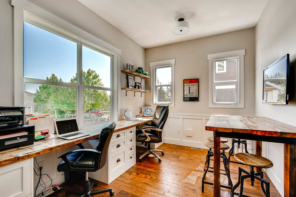 Inredning av ett lantligt litet arbetsrum, med grå väggar, mellanmörkt trägolv, ett inbyggt skrivbord och brunt golv