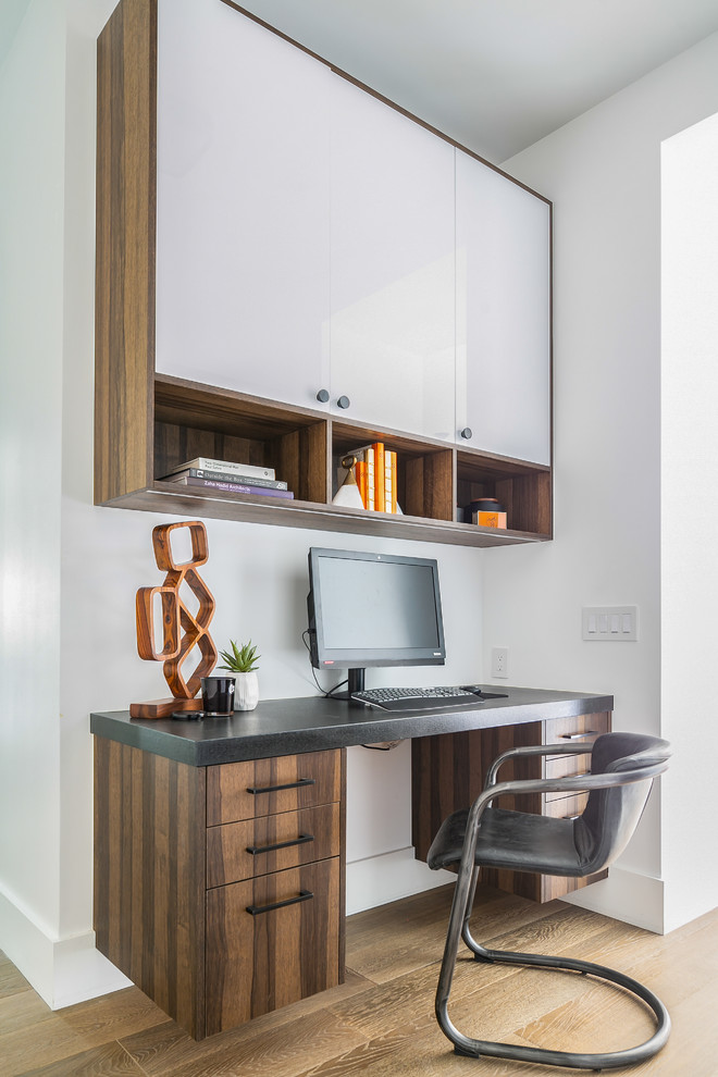 Пример оригинального дизайна: кабинет в современном стиле с белыми стенами, паркетным полом среднего тона, встроенным рабочим столом и коричневым полом