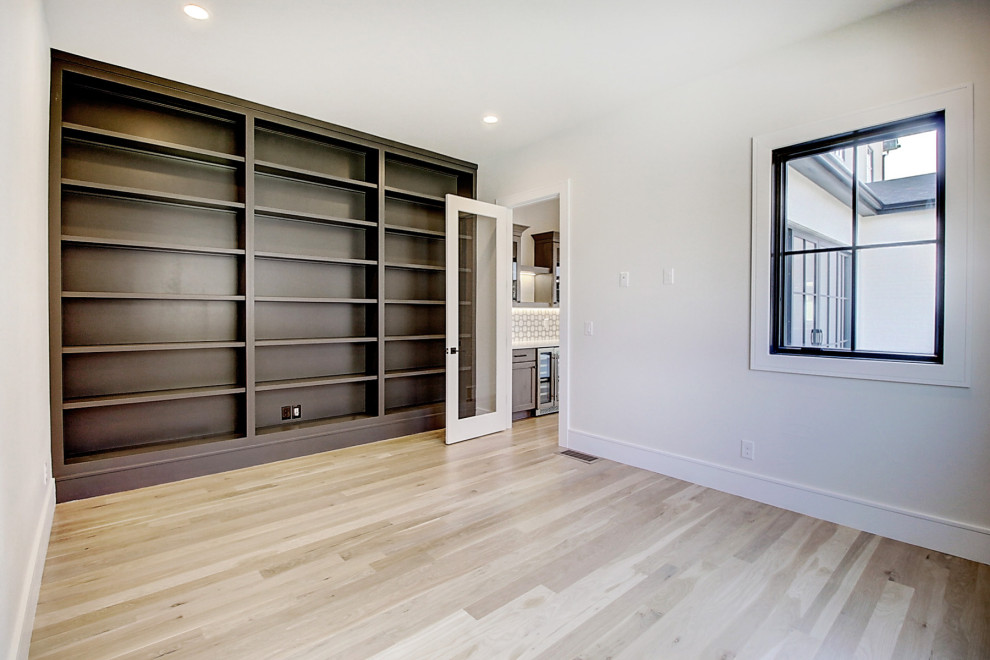 Ejemplo de despacho clásico renovado grande con paredes blancas, suelo de madera clara, escritorio independiente y suelo marrón
