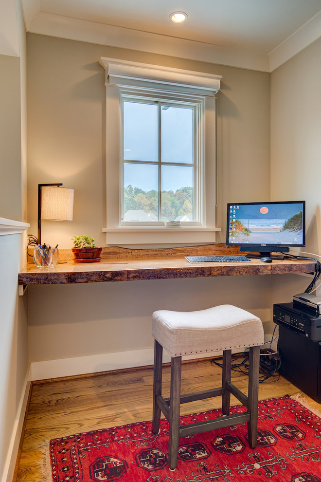Kleines Landhausstil Arbeitszimmer mit beiger Wandfarbe, braunem Holzboden und Einbau-Schreibtisch in Sonstige