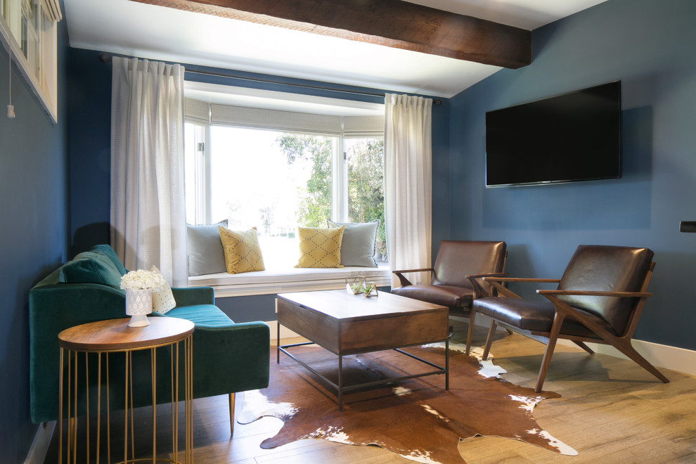 Lantlig inredning av ett mellanstort hemmastudio, med blå väggar, mellanmörkt trägolv och ett fristående skrivbord