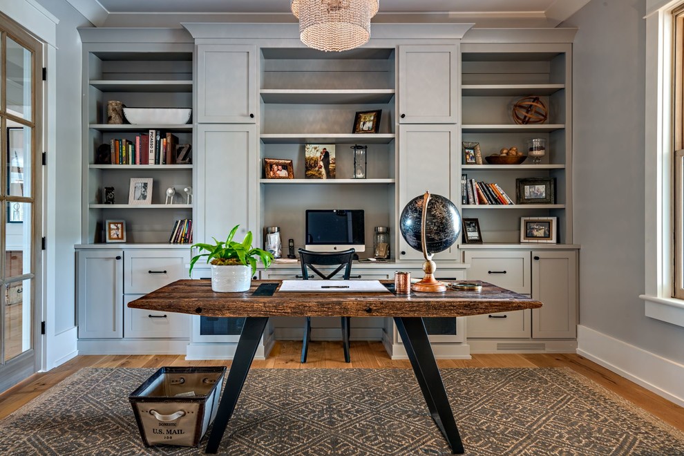 Foto de despacho de estilo de casa de campo de tamaño medio sin chimenea con paredes grises, suelo de madera en tonos medios, escritorio independiente y suelo marrón