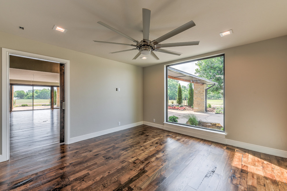 Großes Landhausstil Arbeitszimmer ohne Kamin mit grauer Wandfarbe, dunklem Holzboden und braunem Boden in Oklahoma City