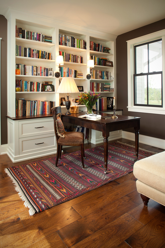 Источник вдохновения для домашнего уюта: домашняя библиотека в стиле неоклассика (современная классика) с коричневыми стенами, паркетным полом среднего тона и отдельно стоящим рабочим столом