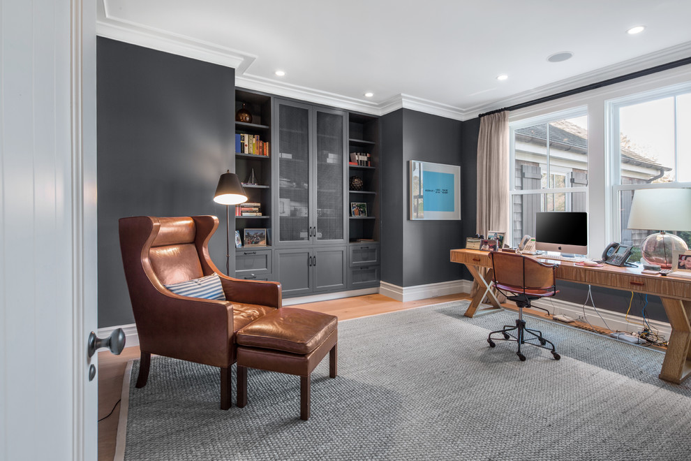Mittelgroßes Klassisches Arbeitszimmer ohne Kamin mit grauer Wandfarbe, braunem Holzboden, freistehendem Schreibtisch, braunem Boden und Arbeitsplatz in New York