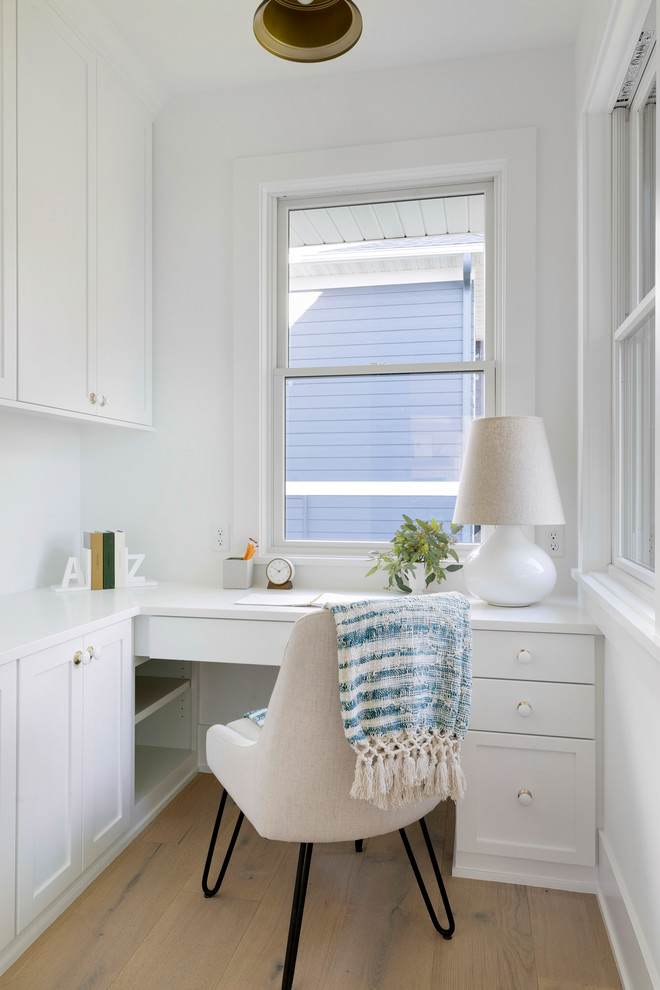 Imagen de despacho de estilo de casa de campo sin chimenea con paredes blancas, suelo de madera clara, escritorio empotrado y suelo beige