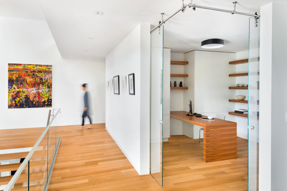 Foto de despacho minimalista sin chimenea con paredes blancas, suelo de madera en tonos medios y escritorio empotrado