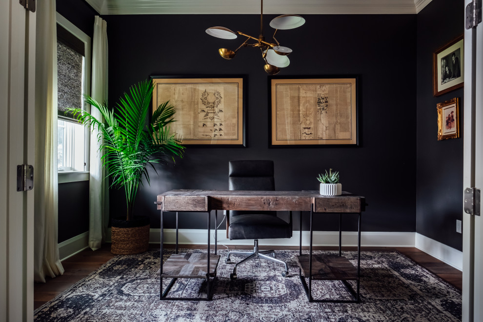 Trendy freestanding desk dark wood floor and brown floor home office photo in Tampa with black walls
