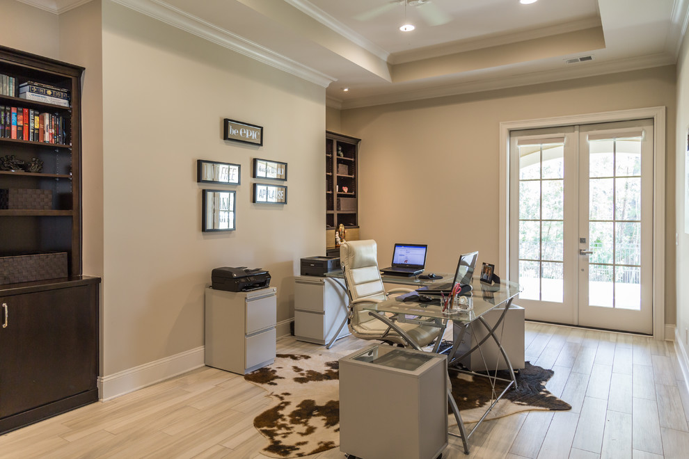 Expansive contemporary study with beige walls, porcelain flooring, a freestanding desk and grey floors.