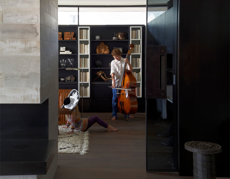 Cette image montre un bureau design de taille moyenne avec un sol en bois brun, une cheminée double-face et un manteau de cheminée en pierre.